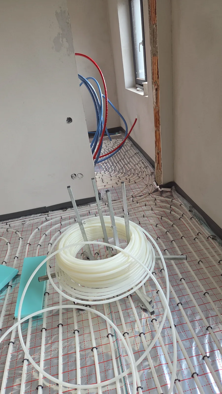 Țeavă PEX în spirale pe folie cu caroiaj, cu colacul de țeavă pe derulator